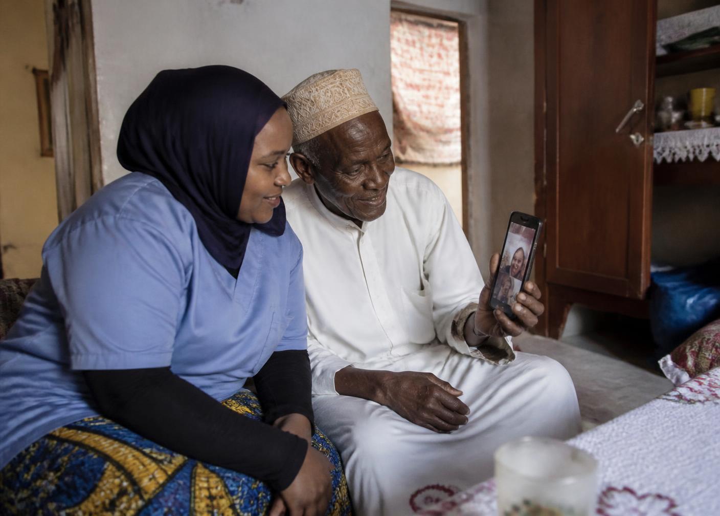 Une accompagnante aide un homme âgé comorien à échanger avec sa famille installée à l’étranger